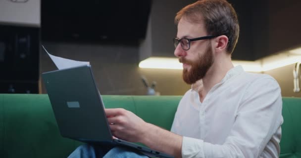 Attaractive Man Shirt Eyeglasses Sitting Sofa Working Laptop Computer Documents — Stockvideo