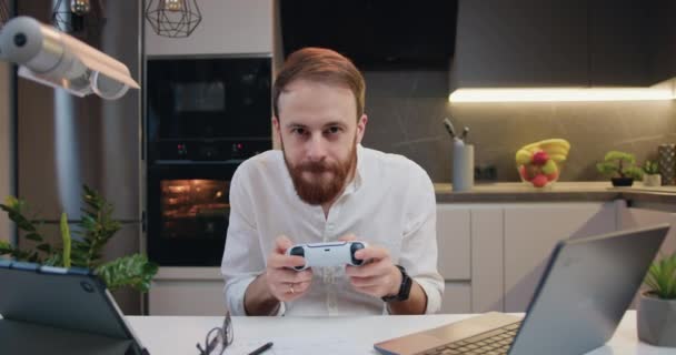 中年微笑的男人在现代化厨房的公寓里玩电子游戏 享受室内活动 在线娱乐和休闲活动概念 — 图库视频影像