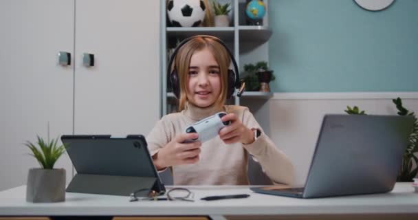 漂亮而兴奋的年轻高加索游戏玩家女孩坐在桌旁 用无线控制杆玩电子游戏 慢动作 — 图库视频影像