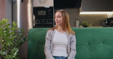 Kanepede oturmuş kameraya bakan gülümseyen güzel bir kadının portresi. Evde tek başına poz veren gülümseyen kız. İçerideki kendine güvenen genç bayanın vesikalığı. Yavaş çekim.