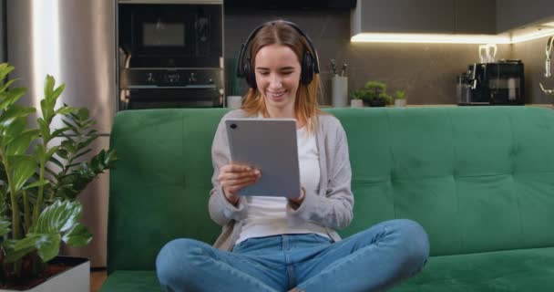Mutlu Gülümseyen Kadın Dijital Tablet Taraması Yapıyor Internetten Kulaklıkla Video — Stok video