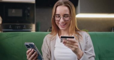 İnternetten akıllı telefon alışverişi yapan gözlüklü güzel bir kadının portresi kredi kartını giriyor. Para transfer ederken kredi kartı kullanan, online alışveriş yapan, yemek siparişi veren bir kız.