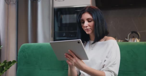 Hermosa Mujer Morena Sentada Sofá Uso Tableta Digital Durante Tiempo — Vídeos de Stock