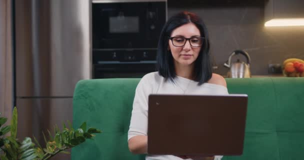 Yeşil Kanepede Oturan Gözlüklü Çekici Esmer Kadını Yakından Çek Bilgisayarında — Stok video