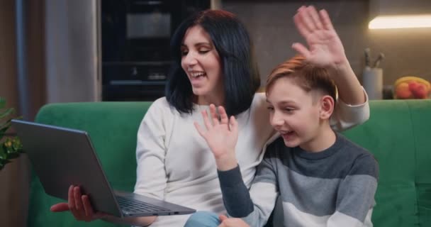 漂亮的女人 与可爱的9岁男孩坐在沙发上 手持笔记本电脑 与家人在视频聊天 快乐的家庭和现代技术 慢动作 — 图库视频影像