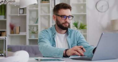 İşadamı odaklı girişimci bilgisayarında daktilo yazarak ofis masasında oturuyor uzaktan çalışan notlar alıyor. Freelancer ev hazırlama raporundan laptopunu iş için kullanıyor. Yavaş çekim.