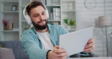 Adam oyuncu elinde dijital tabletle kulaklıkla oturma odasının içinde video oyunu oynuyor. Esport yayın oyunu çevrimiçi. Oyun eğlencesi. Yavaş çekim.