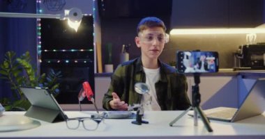 Akıllı ergen öğrenci vlogger, lehimleme ve aletlerle çalışmak için akıllı telefon öğreterek çevrimiçi yayın yapıyor. Genç çocuk akşam evde video blogunu kaydediyor. Yavaş çekim.