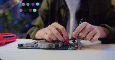 Yakın çekim. Mikro devreyi lehimleyen mühendis. Bilinmeyen bir erkek eli, evdeki masada elektronik bir alet ve tornavida tamir ediyor. Yavaş çekim.