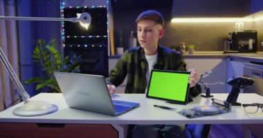 Laptop kullanan çekici bir çocuk video konferansı düzenliyor. Ergen, çağrı videosu sırasında yeşil ekranlı tablet gösteriyor. Chroma anahtar teknolojisi, pazarlama tasarım konsepti.