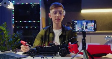 Akıllı telefon ekranına odaklan. Öğrenci vlogger, akıllı telefon öğretimlerini kullanarak çevrimiçi yayın yapıyor. Uzaktan kumandalı oyuncak arabasını tamir ediyor ve dikkatlice oyuncak araba monte ediyor.