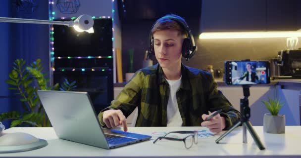 Knappe Mannelijke Jongen Social Media Blogger Hoofdtelefoon Kijkt Naar Laptop — Stockvideo