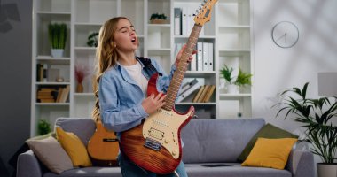 Enerjik funky aktif kız elektro gitar ile müzik çalıyor dans ediyor ve şarkı söylüyor.