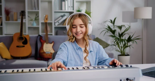 Uśmiechnięta Dziewczyna Białym Słuchawku Ucząca Się Grająca Muzykę Fortepianową Salonie — Zdjęcie stockowe