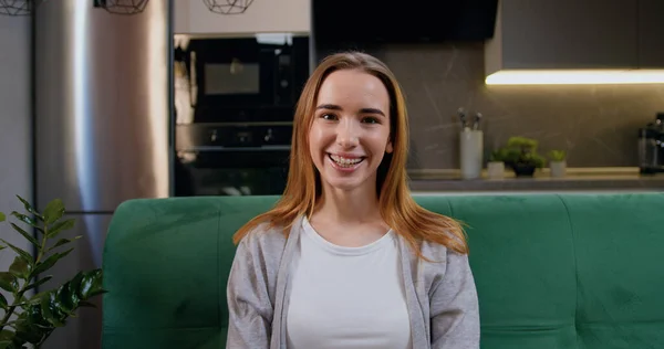 stock image Portrait of smiling pretty woman looking at camera sitting on sofa. Close-up smiling girl posing alone at home. Headshot of confident teen lady indoors.