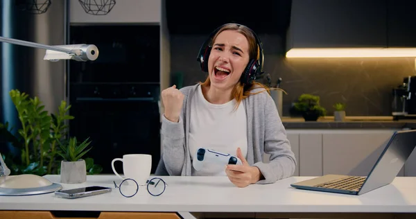 Genç bir kız, modern mutfak dairesinde video oyunu oynuyor ve içeride eğleniyor. Çevrimiçi eğlence ve eğlence etkinliği kavramı.