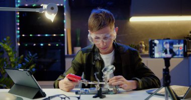 Çocuk vlogger akıllı telefonu kullanarak online yayın yapıyor. Bilim projesinde elektronik ve lehimleme kabloları ve devre kartlarını inceliyor ve evde takipçilere öğretiyor..
