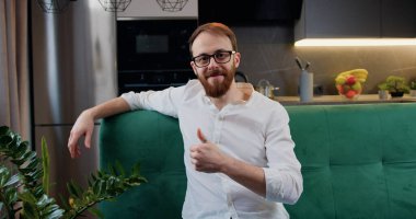 Beyaz mutfak arka planında kameraya bakıp poz veren neşeli, güler yüzlü beyaz bir beyaz adamın portresi..