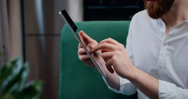 Dijital tablet ekranına dokunan adam, yakın çekim elleri. Koltuk mesafesinde oturan iş adamı, tablet için çalışıyor. Şirket yatırımcılarıyla sohbet ediyor..