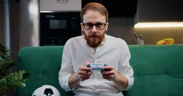 Middle age smilling man playing video game in moderm kitchen apartment enjoying indoor activity. Online entertainment and leisure activity concept.