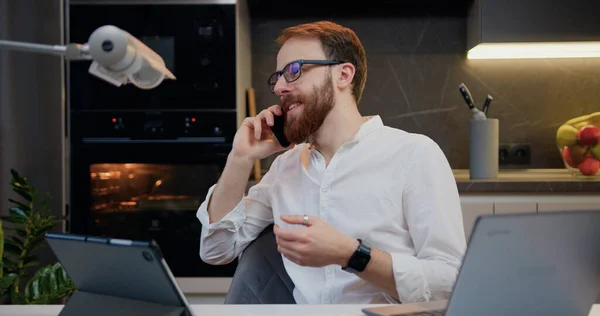 Cep Telefonuyla Konuşan Gülen Dizüstü Bilgisayarla Çalışan Neşeli Bir Adam — Stok fotoğraf