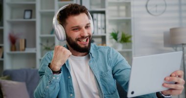 Adam oyuncu elinde dijital tabletle kulaklıkla oturma odasının içinde video oyunu oynuyor. Esport yayın oyunu çevrimiçi. Oyun eğlencesi.