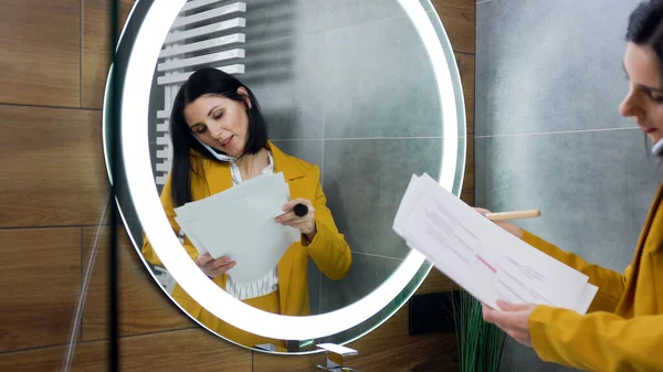 Yakışıklı, ciddi, 30 yaşında, siyah saçlı, şık zeytin takım elbiseli bir iş kadını. Yuvarlak aynanın yanında durmuş, akıllı telefondan konuşuyor ve mali raporları inceliyor.