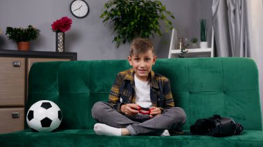 Oturma odasındaki rahat kanepede oturan 10-12 yaşındaki çocuk ve TV 'deki oyun seti uygulamasının keyfini çıkarıyor.