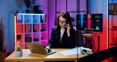 Gözlüklü, sorumluluk sahibi genç bir esmer. Akşam ofisindeki telefon görüşmeleri sırasında kağıt raporlar ve bilgisayar bilgileriyle çalışıyor.