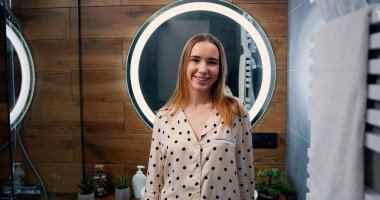 Banyoda kameraya bakan mutlu, gülümseyen çekici kadının portresi. Güzellik, sağlık ve kişisel bakım, evde boş vakitlerin tadını çıkarmak..