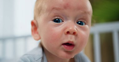 Güzel gülümseyen bebek. Portreye yakın küçük bebek yatakta uzanmış gülümsüyor ve kameraya poz veriyor.