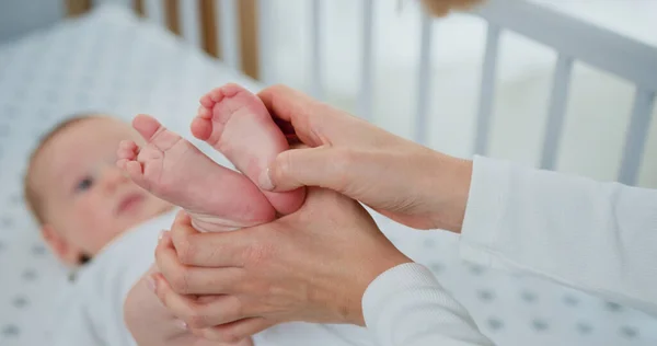 赤ちゃんの足を保持し 優しく完璧な肌で彼の小さな足を手で撫でて女性の閉鎖 ベビーケアのコンセプト — ストック写真