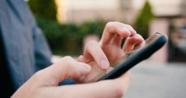 Kapatın. Sokakta dikilirken cep telefonu kullanan beyaz adam elleri. Erkek dinleme ve cep telefonuyla mesajlaşma. Açık havada..