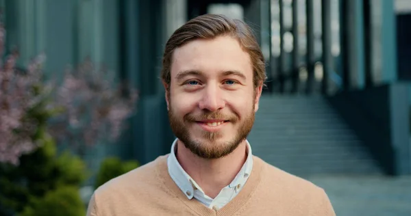 Dışarıda dikilen genç yakışıklının yakın plan portresi. Kameraya bakıp sırıtarak tek başına gözlüklerini çıkar. İnsan ve yaşam tarzı kavramı.