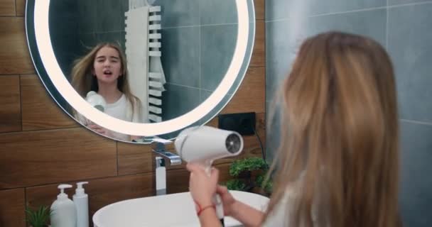 소녀는 헤어드라이어로 머리를 말린다 화장실에서 노래하고 웃는다 귀여운 머리를 헤어드라이어와 — 비디오