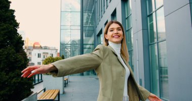 Gülümseyen başarılı genç kadın, güzel bir günde şehir caddesinde yürürken başarıya seviniyor. Yaşam biçimi