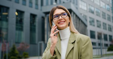 Şehrin finans bölgesinde akıllı telefon kullanan, gözlüklü, başarılı genç sarışın kadını yakından çek. Açık havada..