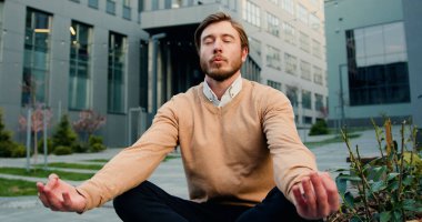 Yakışıklı, beyaz sakallı, gözlüklü, dinlenen, nilüfer pozisyonunda oturan ofis binası ya da üniversitenin avlusunda oturan. Sağlıklı yaşam tarzı, açık hava.