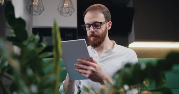 Evde Çalışan Elinde Ped Bilgisayarıyla Odaklanmış Serbest Çalışan Bir Adam — Stok video