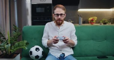 Modern mutfak dairesinde video oyunu oynayan odaklanmış bir adam içeride eğleniyor. Çevrimiçi eğlence ve eğlence aktivitesi konsepti. Yavaş çekim.