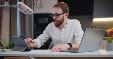 Ofiste çalışmak için dizüstü bilgisayar kullanan yakışıklı beyaz bir adam. İş adamı evde dizüstü bilgisayar ekranına bakarak serbest çalışmanın tadını çıkarıyor. Yavaş çekim.