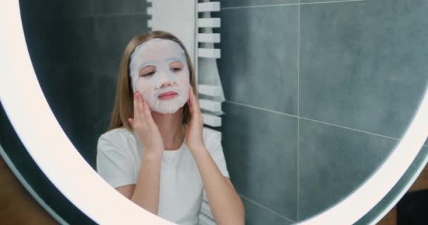 可爱的年轻漂亮的女孩在家里的浴室里使用化妆品保湿面膜 少女皮肤护理治疗 慢动作 — 图库视频影像