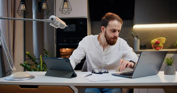 stock image Portrait of happy man use laptop and tablet typing browsing found out great win good news celebrate victory at home room apartment. Joyful boy reading good news on computer.