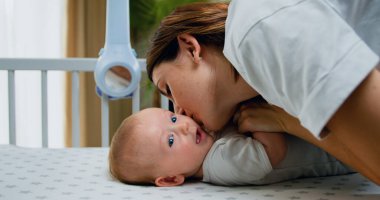 Mutlu anne küçük bebek güneşiyle öpüşürken gülümsüyor. Ebeveyn, çocuk kızı eğlendirir. Anne ve küçük bebek, yakın plan.