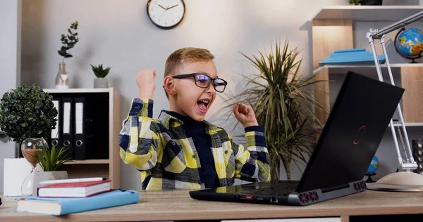 フロントビューの可能性のあるスマート現代のティーン学校の少年で眼鏡でそれは自宅でコンピュータに座って — ストック写真