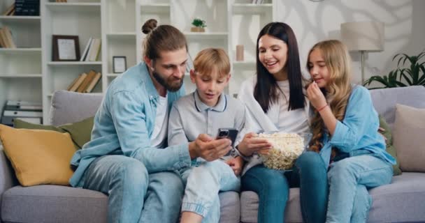 母亲和可爱的小孩在手机上看有趣的社交媒体视频 年轻家庭使用现代无线技术观看博客 享受免费上网时间 慢动作 — 图库视频影像