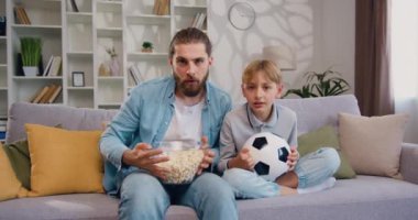 Komik sarışın çocuk birlikte vakit geçiriyor hangi baba, televizyonda futbol maçı izleyip duygusal tepki veriyor. Futbol takımının zaferini kutlayan heyecanlı taraftarlar. Yavaş çekim.