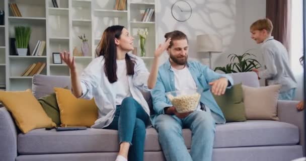 Familienvater Und Mutter Sitzen Genervt Auf Dem Sofa Zwei Fröhliche — Stockvideo