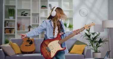Enerjik, uzun saçlı, elektro gitar çalan, evdeki oturma odasında şarkı söyleyen ve dans eden komik kız. 11-12 yaşlarında elektro gitarla rock çalan çekici bir kız. Yavaş çekim