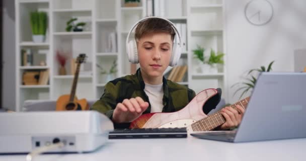 Привлекательный Летний Мальчик Наушниках Играющий Гитаре Смотрит Ноутбук Дома Портрет — стоковое видео